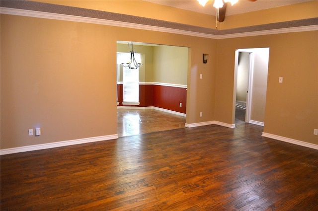 empty room featuring dark wood-type flooring, ornamental molding, and ceiling fan with notable chandelier