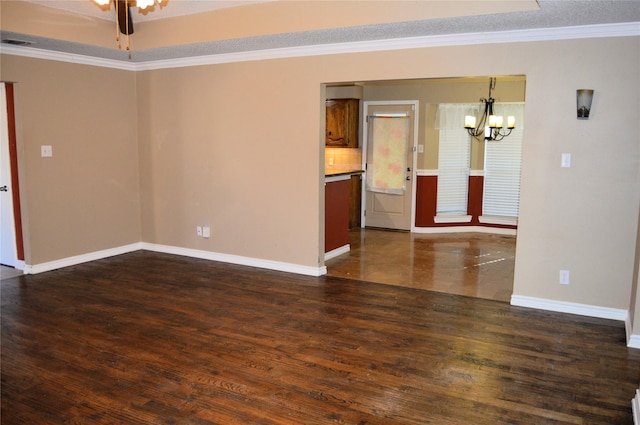 empty room with ornamental molding, dark hardwood / wood-style floors, and a notable chandelier