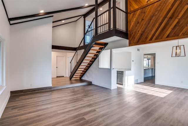 unfurnished living room with a chandelier, wood-type flooring, and a towering ceiling