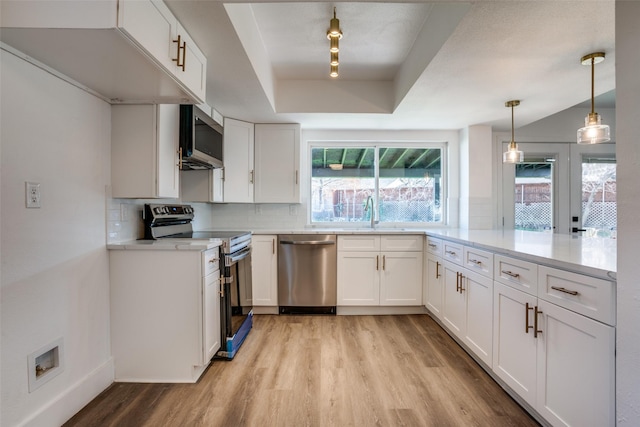 kitchen with white cabinetry, appliances with stainless steel finishes, a tray ceiling, and decorative backsplash