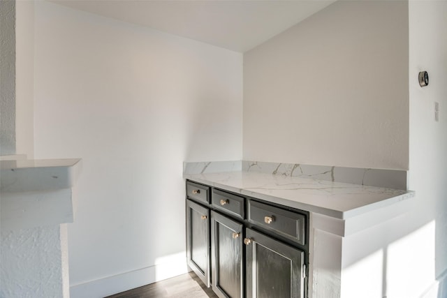 bar featuring light stone counters and light hardwood / wood-style floors