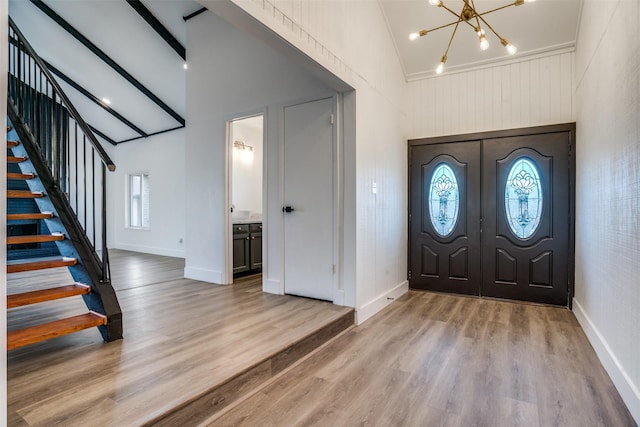 entrance foyer featuring french doors, light wood-type flooring, vaulted ceiling, and a notable chandelier