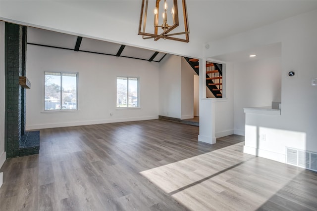 unfurnished living room featuring hardwood / wood-style flooring, an inviting chandelier, and vaulted ceiling