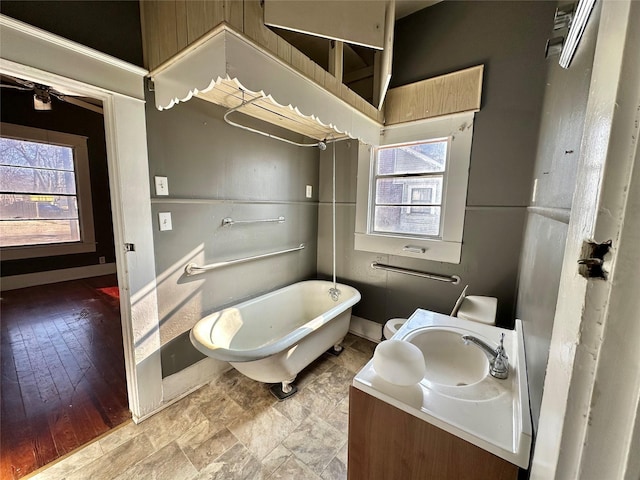 bathroom with vanity, a healthy amount of sunlight, baseboards, and a freestanding bath