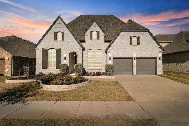 french provincial home featuring a lawn and a garage