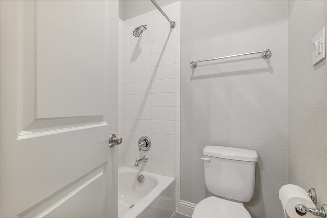 bathroom with tiled shower / bath combo and toilet