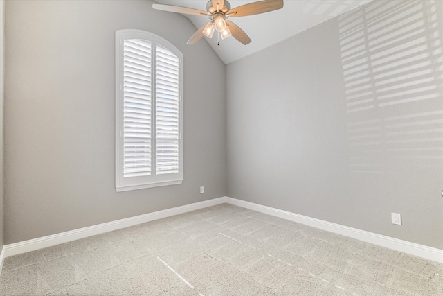 carpeted empty room featuring lofted ceiling, a ceiling fan, and baseboards