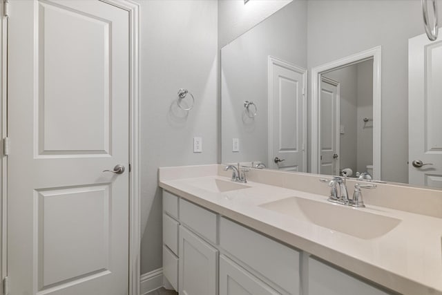 full bathroom featuring toilet, double vanity, and a sink
