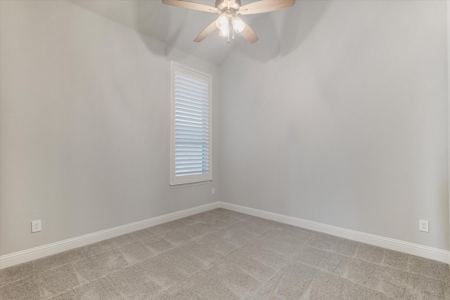 empty room featuring a ceiling fan, vaulted ceiling, light colored carpet, and baseboards
