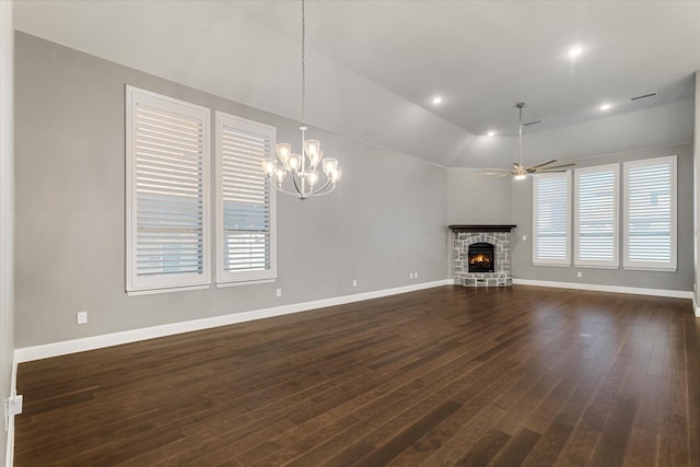 unfurnished living room featuring a stone fireplace, ceiling fan with notable chandelier, dark hardwood / wood-style floors, and vaulted ceiling