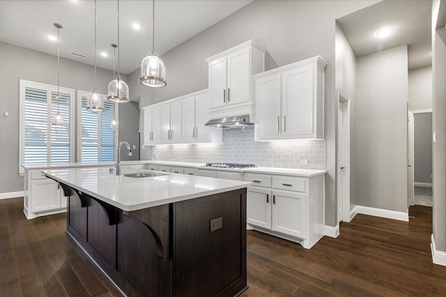 kitchen with decorative backsplash, light countertops, dark wood-style flooring, and a sink