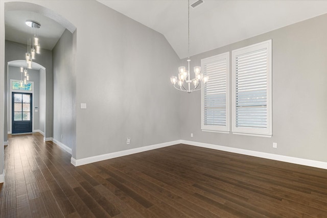 spare room featuring dark hardwood / wood-style floors, vaulted ceiling, and a notable chandelier