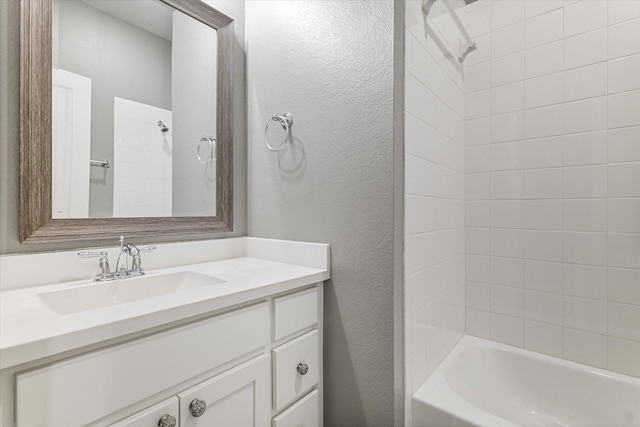 full bath featuring a textured wall, vanity, and washtub / shower combination