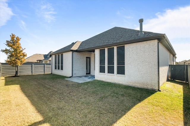 rear view of house with brick siding, a fenced backyard, a shingled roof, and a yard