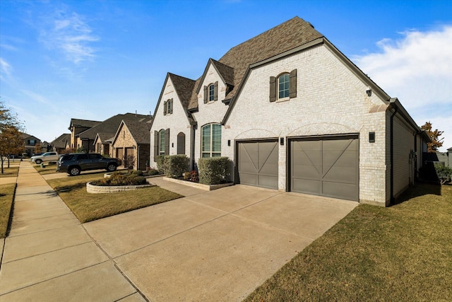 french provincial home featuring a garage and a front lawn