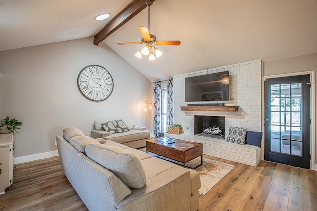 living room with vaulted ceiling with beams, hardwood / wood-style flooring, a fireplace, and ceiling fan