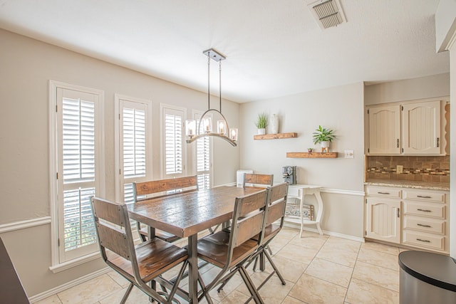 dining space with light tile patterned flooring, a notable chandelier, and a textured ceiling