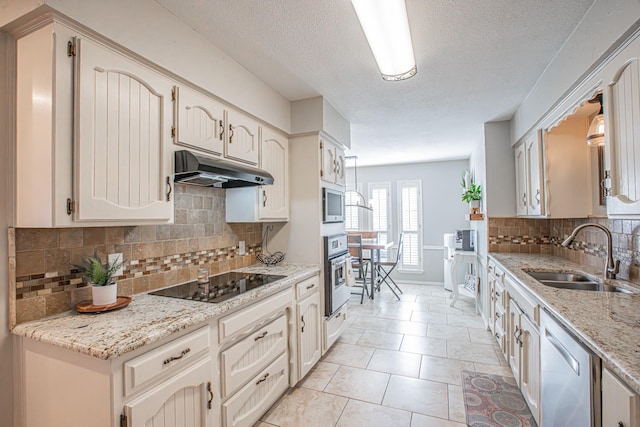 kitchen with light stone counters, stainless steel appliances, sink, and decorative backsplash