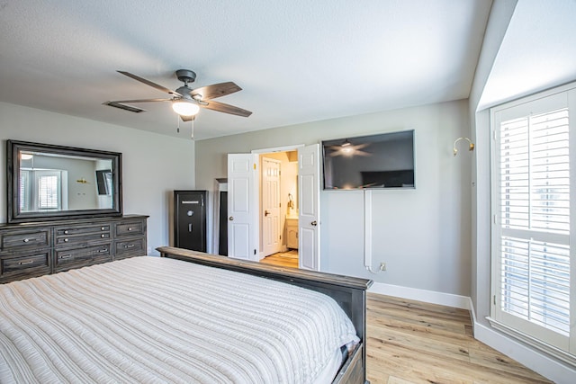 bedroom with connected bathroom, a textured ceiling, light hardwood / wood-style flooring, and ceiling fan