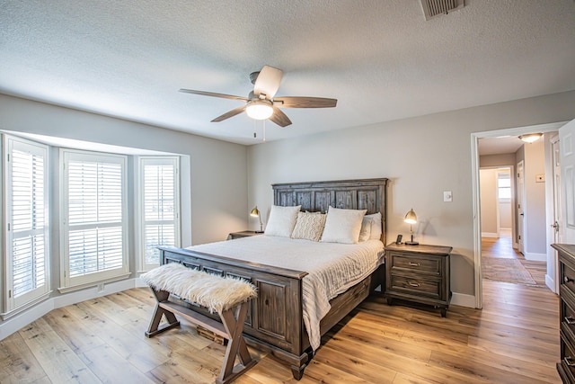 bedroom with ceiling fan, a textured ceiling, and light wood-type flooring