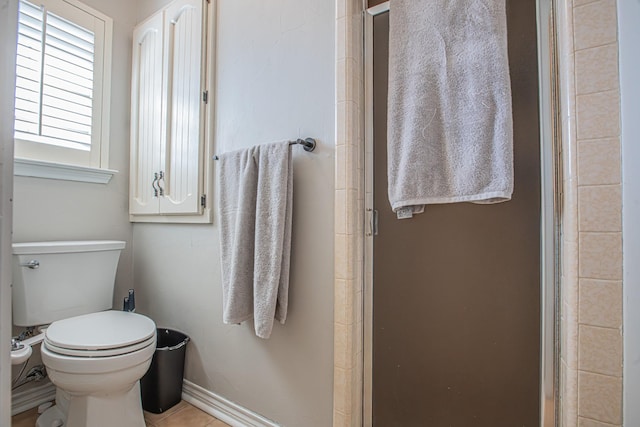 bathroom with a shower with door and toilet