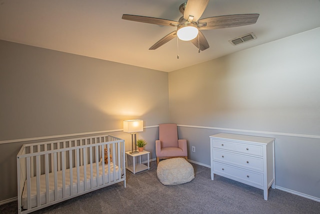 carpeted bedroom featuring a nursery area and ceiling fan