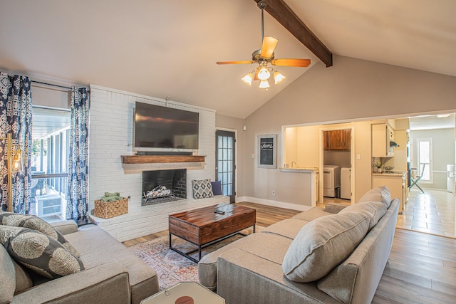 living room with beam ceiling, washing machine and dryer, a fireplace, and light hardwood / wood-style floors