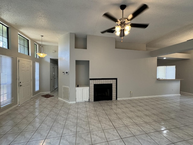 unfurnished living room with plenty of natural light, light tile patterned floors, a textured ceiling, and a fireplace