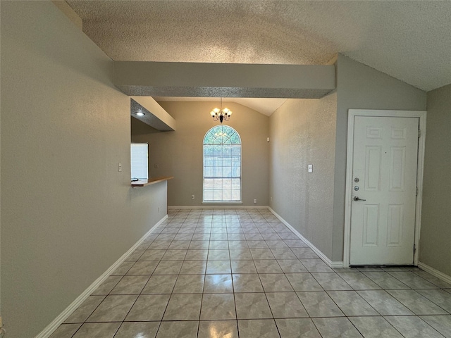 tiled entrance foyer featuring vaulted ceiling, a textured ceiling, and a chandelier