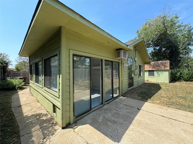 view of property exterior featuring a lawn, a wall mounted air conditioner, a patio area, and a shed