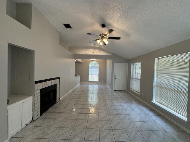 unfurnished living room featuring vaulted ceiling, light tile patterned floors, ceiling fan, a brick fireplace, and a textured ceiling