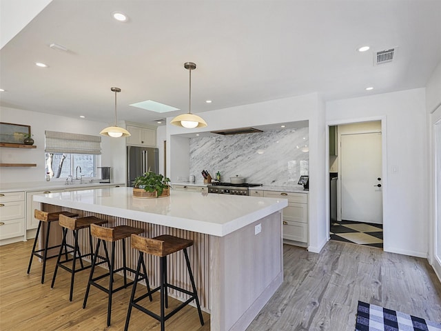 kitchen featuring pendant lighting, tasteful backsplash, a large island, high end fridge, and a breakfast bar area