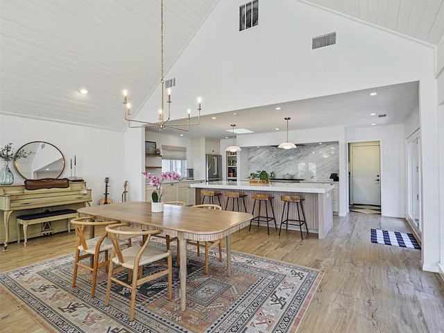 dining space featuring light hardwood / wood-style flooring, high vaulted ceiling, wooden ceiling, and a notable chandelier