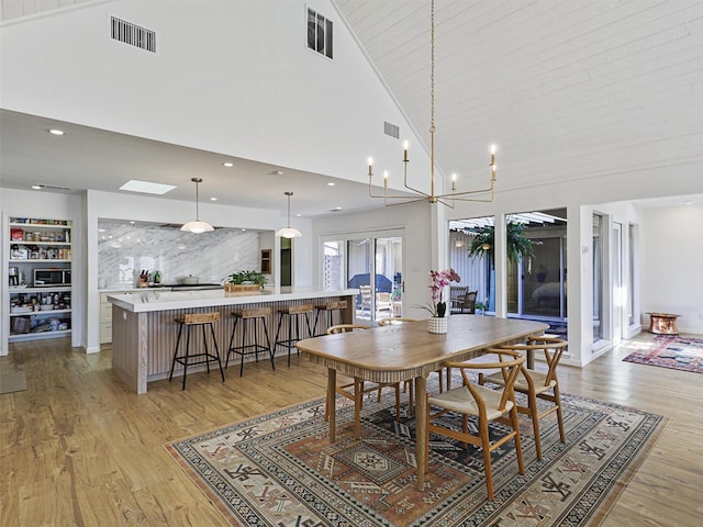 dining space with a chandelier, light hardwood / wood-style flooring, and high vaulted ceiling