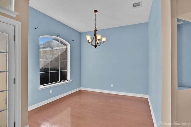 unfurnished dining area featuring an inviting chandelier and hardwood / wood-style floors