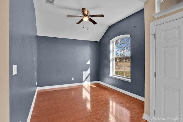 empty room with hardwood / wood-style flooring, vaulted ceiling, and ceiling fan