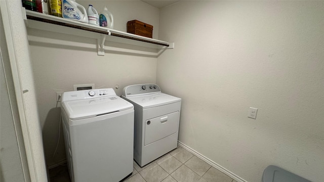 clothes washing area with light tile patterned floors and washer and clothes dryer