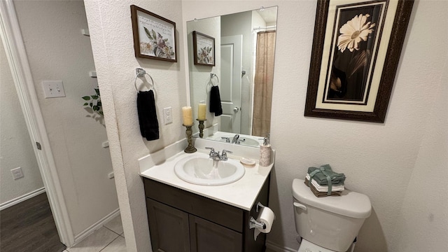 bathroom with toilet, vanity, and tile patterned flooring