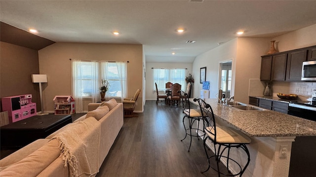 living room featuring vaulted ceiling, dark hardwood / wood-style floors, and sink