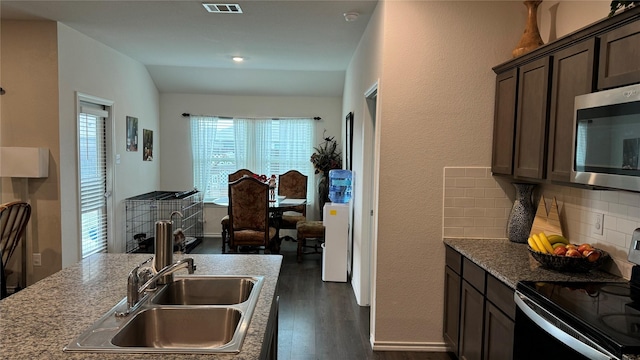 kitchen featuring light stone counters, dark brown cabinetry, range with electric stovetop, and tasteful backsplash