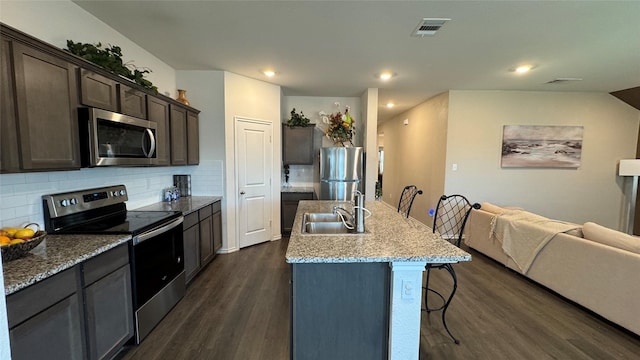 kitchen with decorative backsplash, sink, appliances with stainless steel finishes, an island with sink, and dark hardwood / wood-style flooring