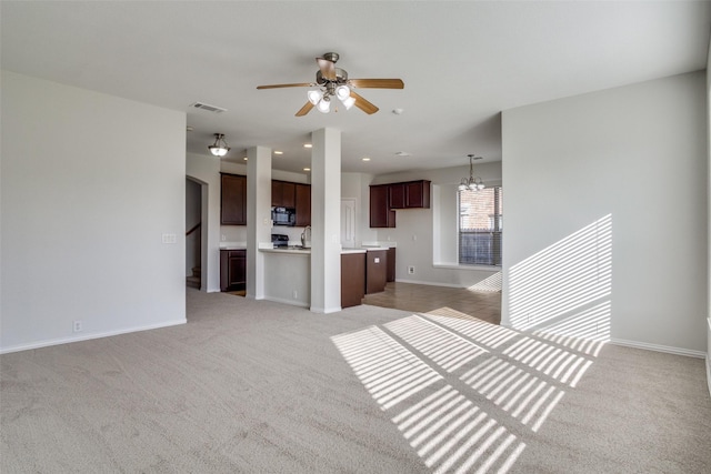 unfurnished living room featuring light colored carpet and ceiling fan with notable chandelier