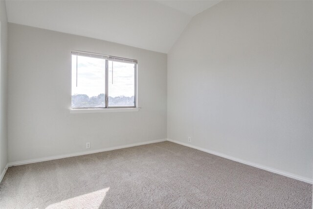 carpeted spare room featuring vaulted ceiling