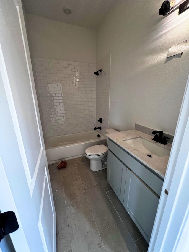 full bathroom with tiled shower / bath, vanity, and toilet