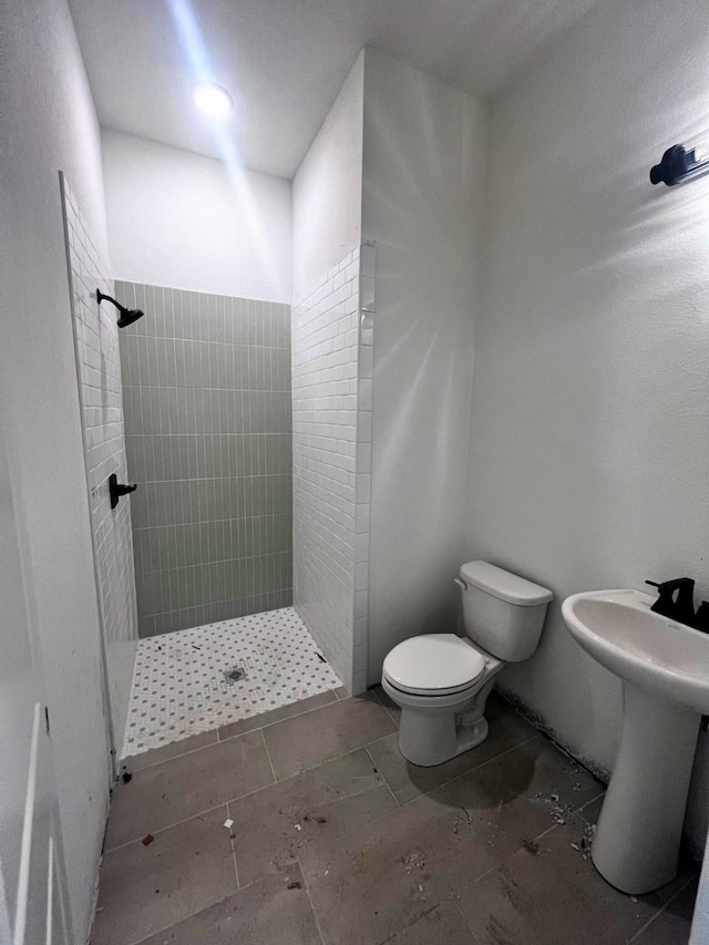 bathroom featuring toilet and a tile shower