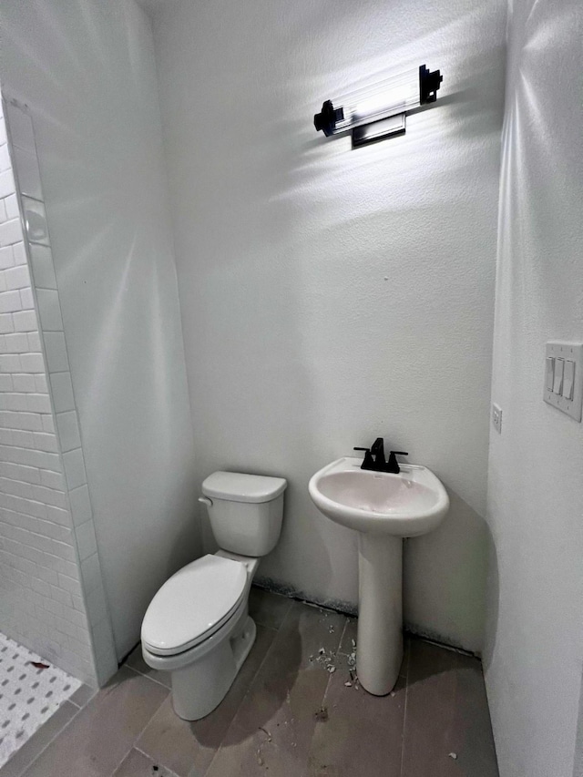 bathroom featuring tiled shower and toilet