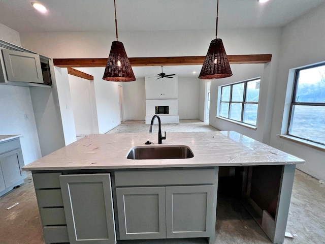 kitchen with light stone countertops, sink, and gray cabinetry