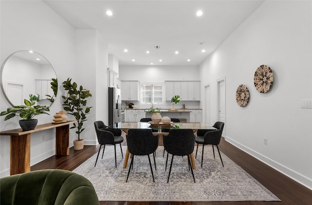 dining room with sink, a towering ceiling, and dark hardwood / wood-style flooring