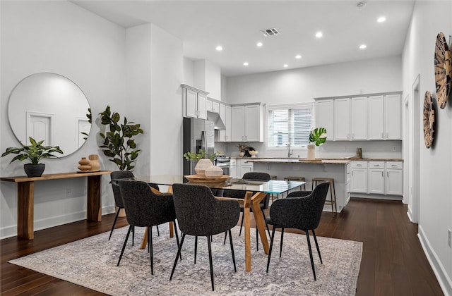 dining space featuring dark wood-type flooring and a towering ceiling