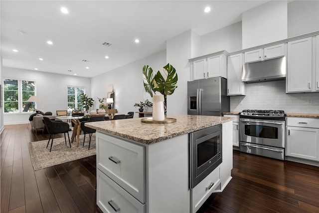 kitchen featuring a center island, dark wood-type flooring, white cabinetry, stainless steel appliances, and tasteful backsplash